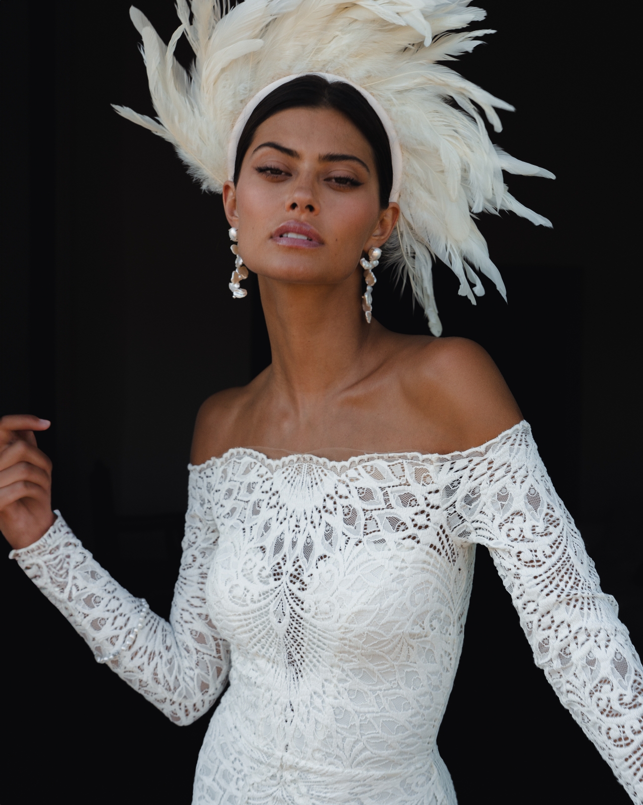 model in lace off the shoulder gown with long sleece and feather head accessory